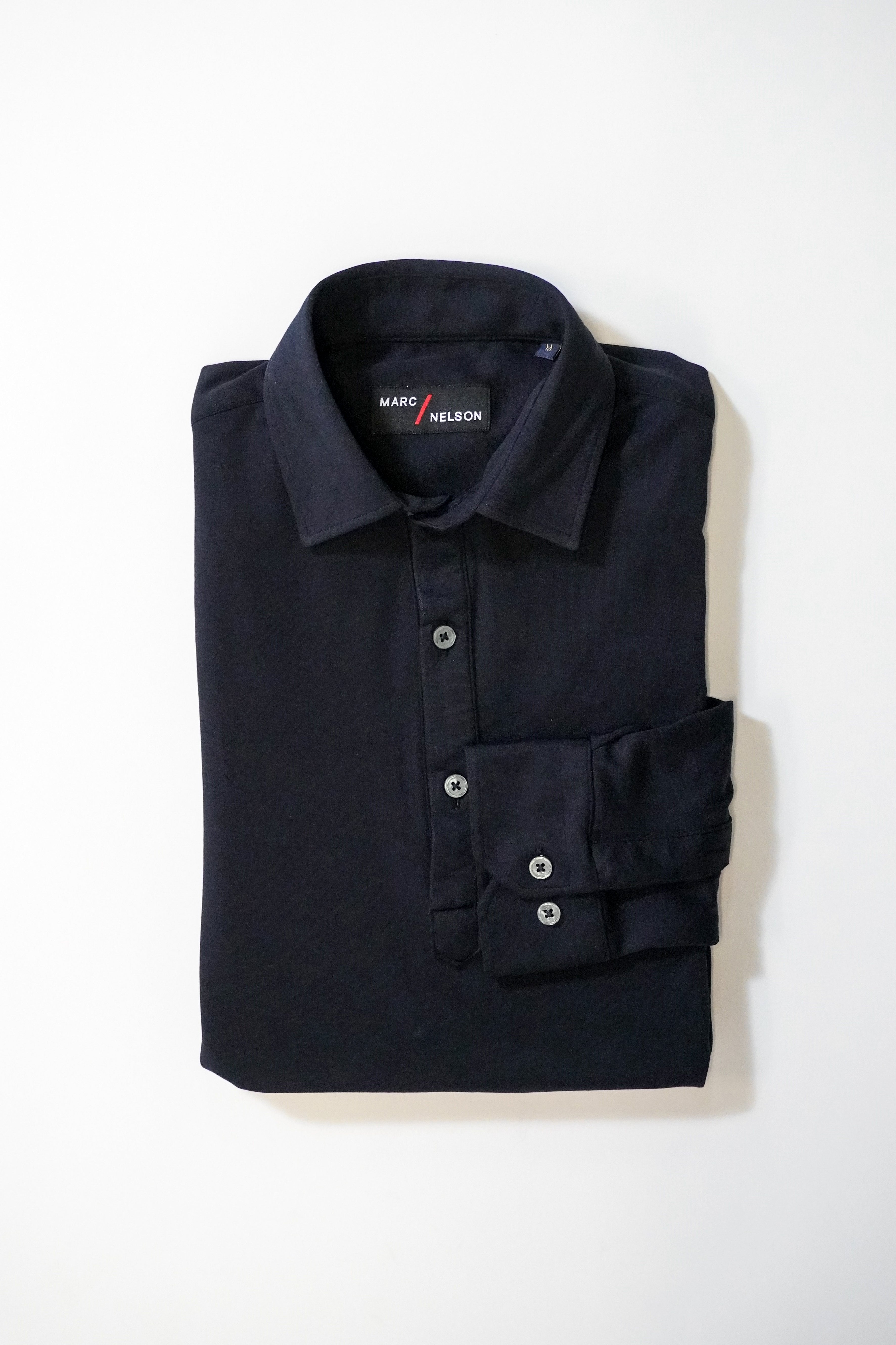 A neatly folded long-sleeve black collared shirt with buttons, displayed on a plain white background. The label inside the collar reads Maro Nelson.